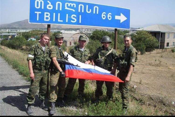 Russian soldiers during 2008 war holding Russian flag near Tbilisi sign
