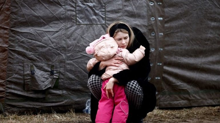 A woman fleeing the Russian invasion of Ukraine embraces a child in a refugee camp in Przemysl, Poland  - фото 1