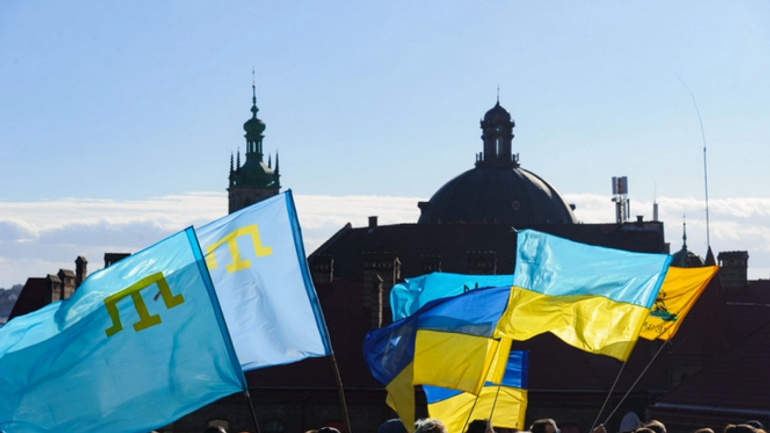 Ukrainian and Crimean Tatar flags are seen in downtown Lviv, Ukraine, on February 19, 2022, during a Unity march. The event showed the readiness of Ukrainians to resist Russian aggression. - фото 1