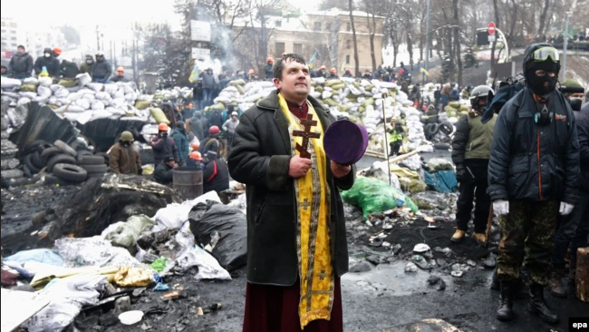 Священик молиться на одній з барикад під час чергового дня антиурядового протесту в Києві, 28 січня 2014 року - фото 72586