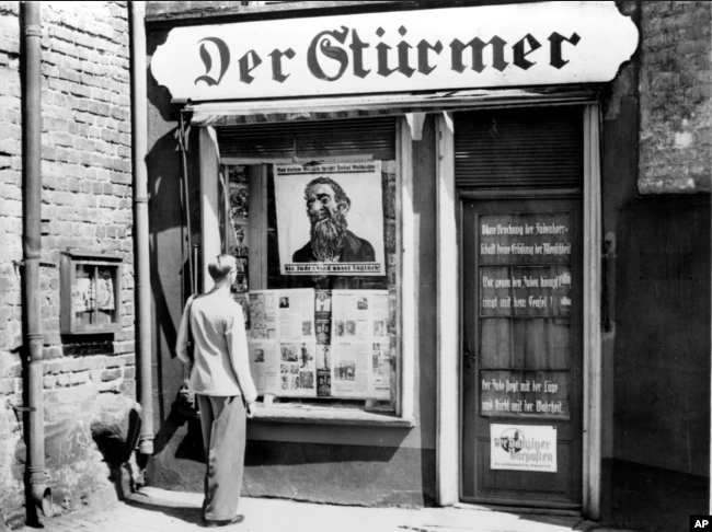 Чоловік дивиться на антисемітську карикатуру, виставлену у вікні офісу антиєврейської газети Der Stuermer під час вторгнення нацистів у «вільне місто» Данциг, Польща, 10 липня 1939 року - фото 79531