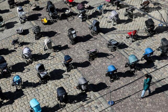 A person looks at 109 empty prams placed in the center of Lviv during the “Price of War” campaign organized by local activists and authorities to highlight the large number of children killed in ongoing Russia’s invasion of Ukraine, in Lviv, March 18.  - фото 89628