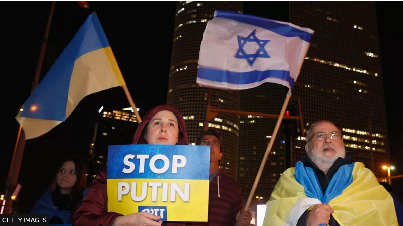 People in the Israeli city of Tel Aviv wave Ukrainian and Israeli flags during a protest against Russia's military invasion of Ukraine in March 2022 - фото 97967