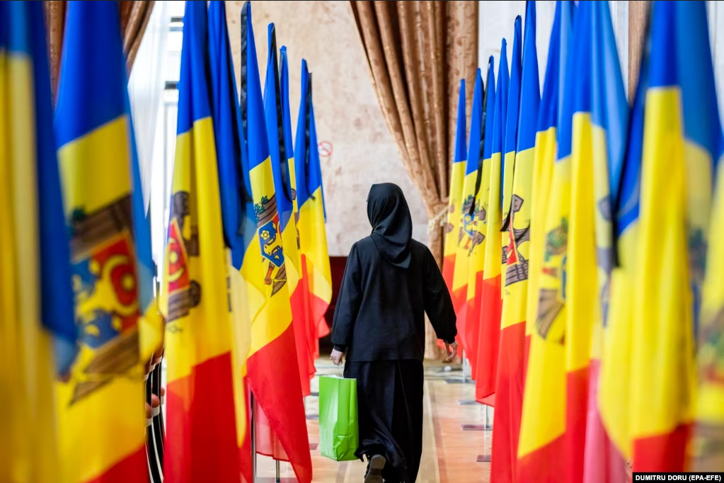 An Orthodox nun walks amid national flags during a funeral ceremony in Chisinau. - фото 124984